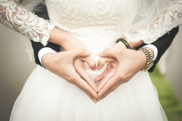 Bride and groom form a heart shape with their hands